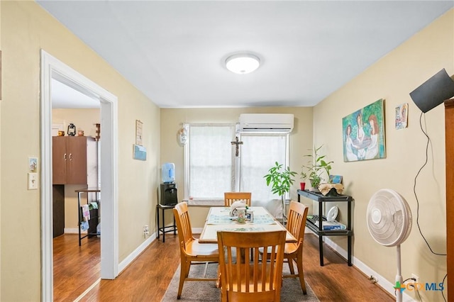 dining area featuring baseboards, wood finished floors, and a wall unit AC