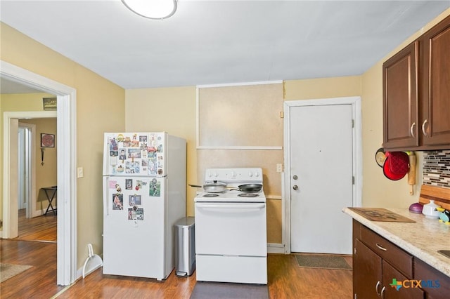 kitchen featuring dark wood-style floors, backsplash, white appliances, and light countertops