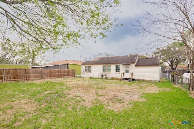 back of property with entry steps, a yard, and a fenced backyard