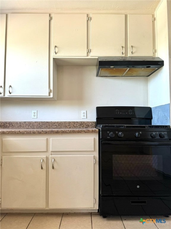 kitchen with black gas range, extractor fan, light tile patterned floors, and white cabinets