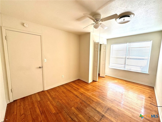 unfurnished bedroom with light hardwood / wood-style floors, ceiling fan, and a textured ceiling