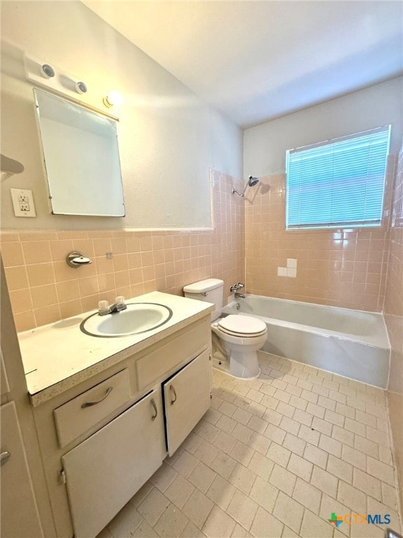 full bathroom featuring tile patterned flooring, vanity, toilet, tile walls, and tiled shower / bath combo