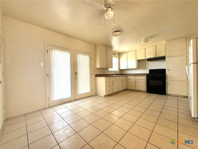 kitchen with white fridge, light tile patterned flooring, black range, sink, and ceiling fan