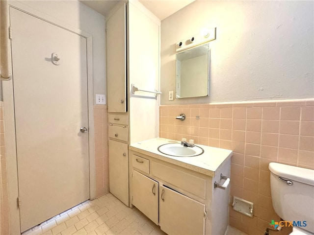 bathroom with tile walls, tile patterned flooring, vanity, and toilet