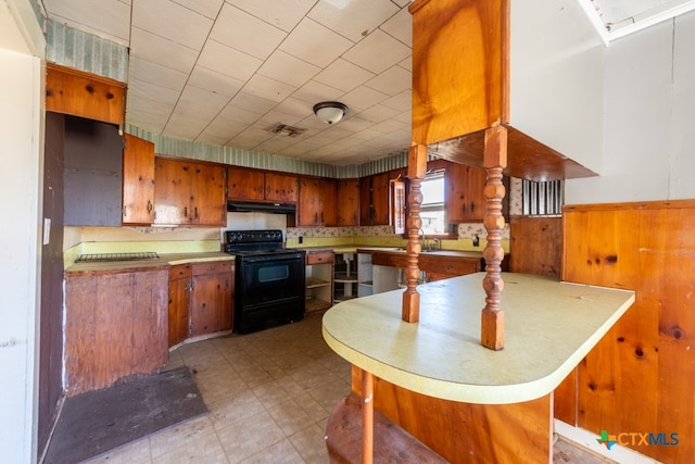 kitchen with wood walls, black range with electric stovetop, and kitchen peninsula