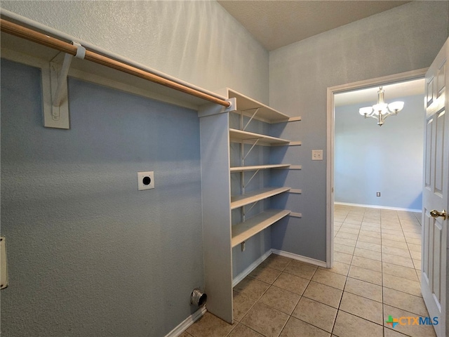 laundry room with electric dryer hookup, light tile patterned floors, and a chandelier