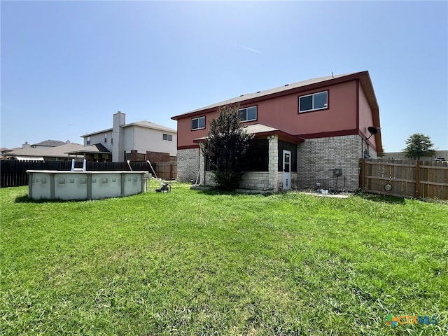 back of house featuring a fenced in pool and a yard