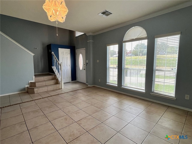 tiled foyer entrance with a wealth of natural light, crown molding, and a chandelier