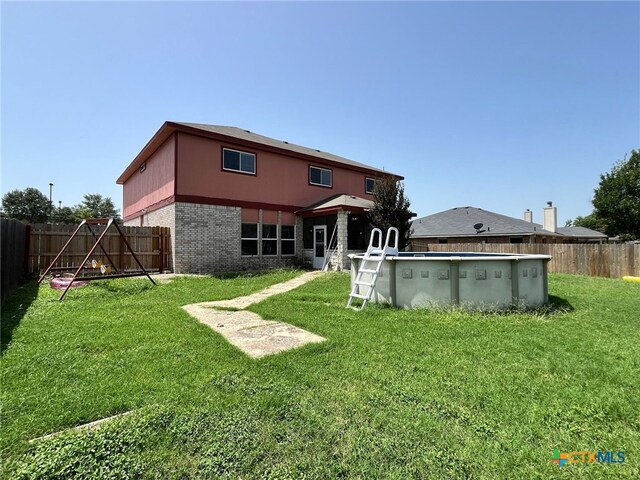 rear view of property featuring a fenced in pool and a lawn