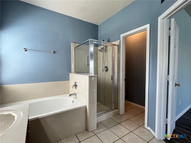 bathroom with tile patterned flooring, shower with separate bathtub, and sink