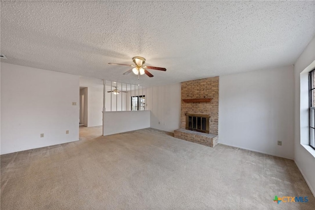 unfurnished living room with light colored carpet, a brick fireplace, a ceiling fan, and a textured ceiling