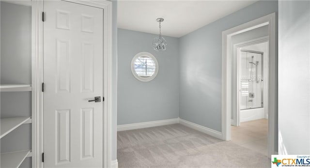 carpeted spare room featuring a chandelier