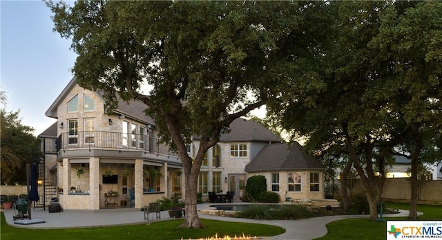 rear view of house featuring a yard, a balcony, and a patio