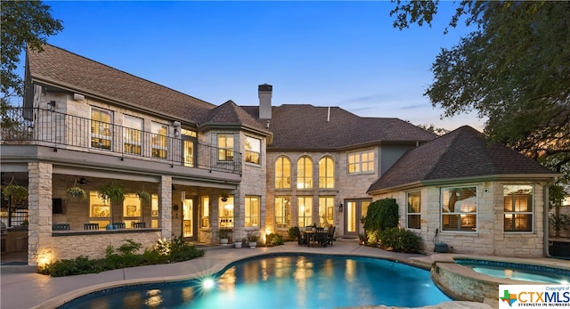 pool at dusk featuring a patio area and an in ground hot tub