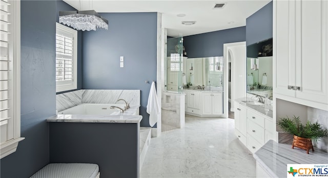 bathroom with a bathing tub, a chandelier, vanity, and a healthy amount of sunlight