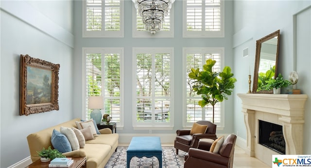 sunroom / solarium featuring an inviting chandelier and a tiled fireplace