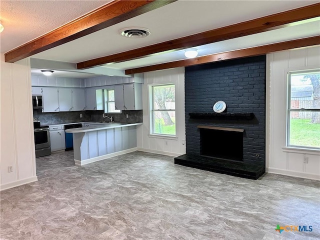 2303 Bon Aire Ave, Victoria, TX 77901 - kitchen featuring stainless steel appliances, beamed ceiling, a peninsula, healthy amount of natural light, and light countertops