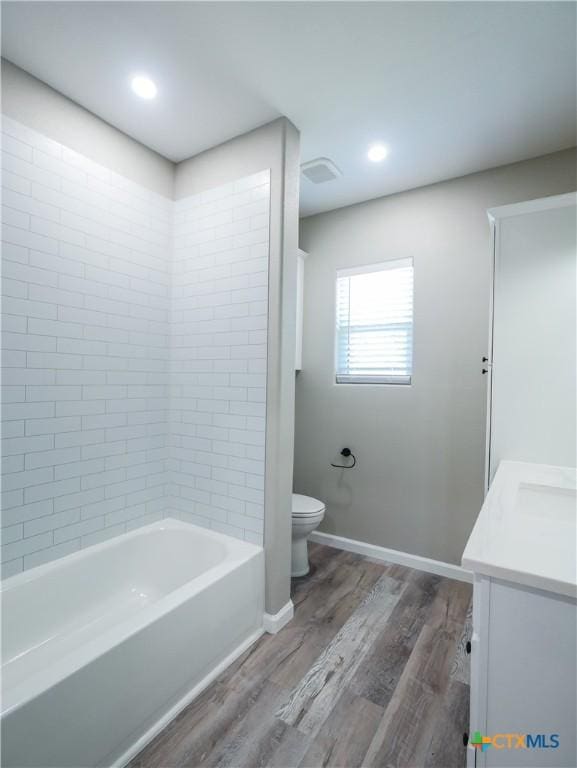 full bathroom with vanity, wood-type flooring, tiled shower / bath combo, and toilet