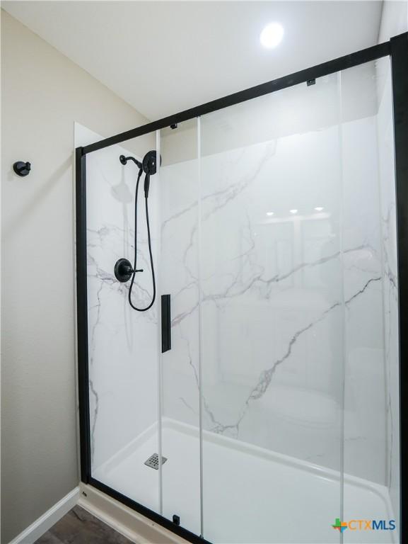 bathroom with wood-type flooring and a shower with door