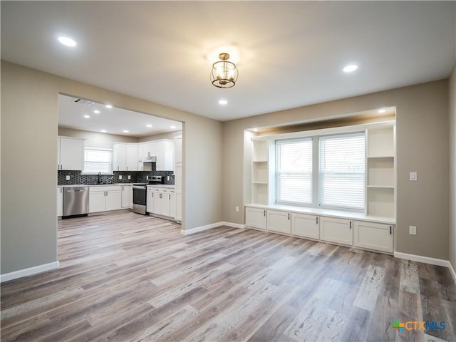 kitchen with backsplash, stainless steel appliances, sink, light hardwood / wood-style flooring, and white cabinets