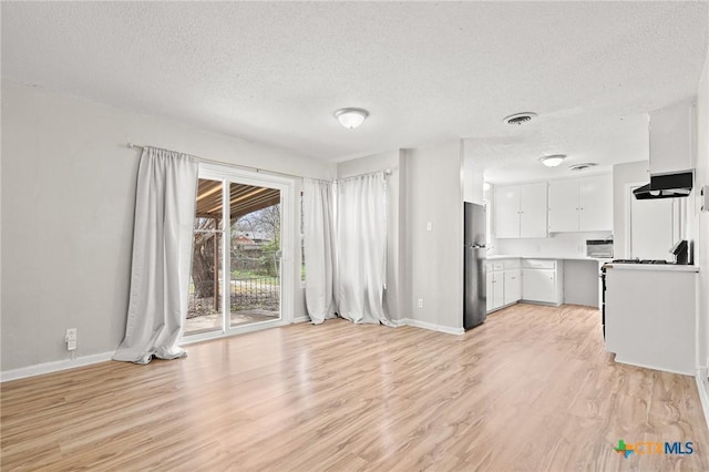 unfurnished living room featuring a textured ceiling, light wood finished floors, visible vents, and baseboards