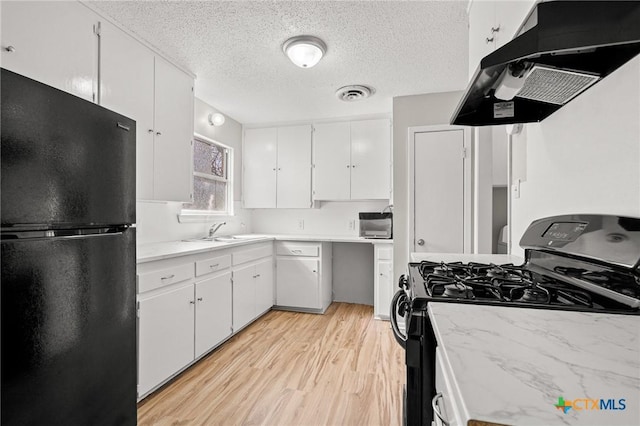 kitchen with under cabinet range hood, a sink, white cabinets, light countertops, and black appliances