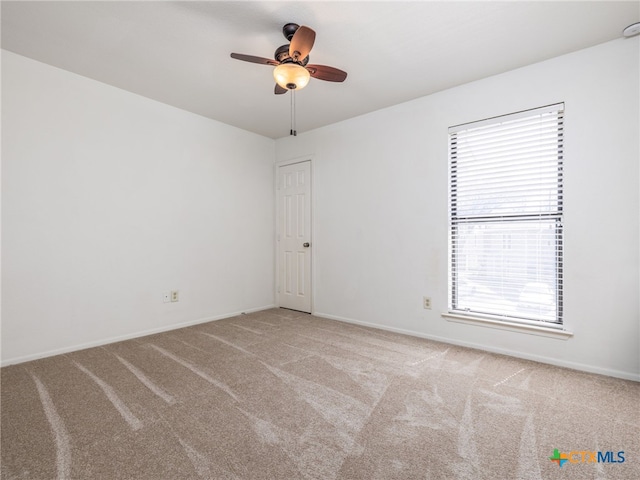 carpeted empty room with ceiling fan and baseboards