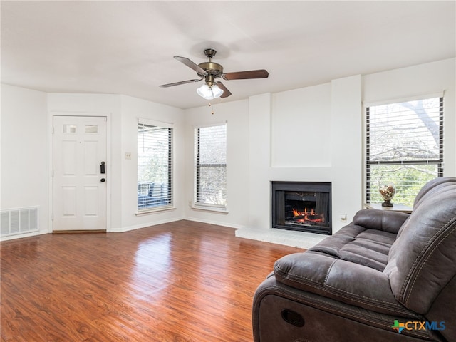 living room with baseboards, a lit fireplace, visible vents, and wood finished floors