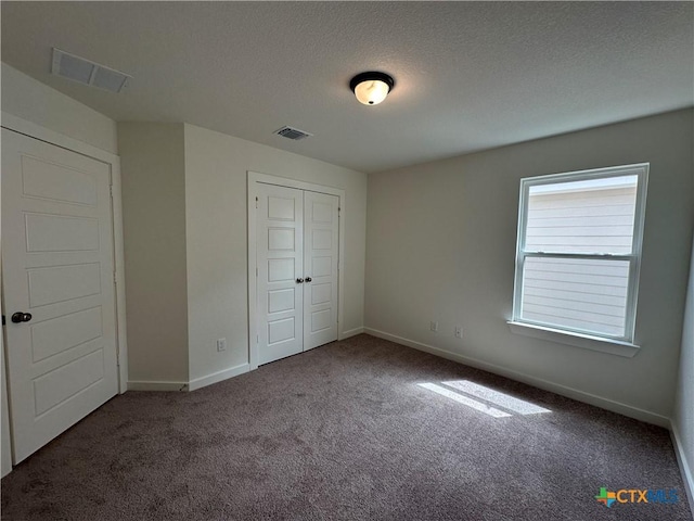 unfurnished bedroom with baseboards, visible vents, carpet floors, and a textured ceiling