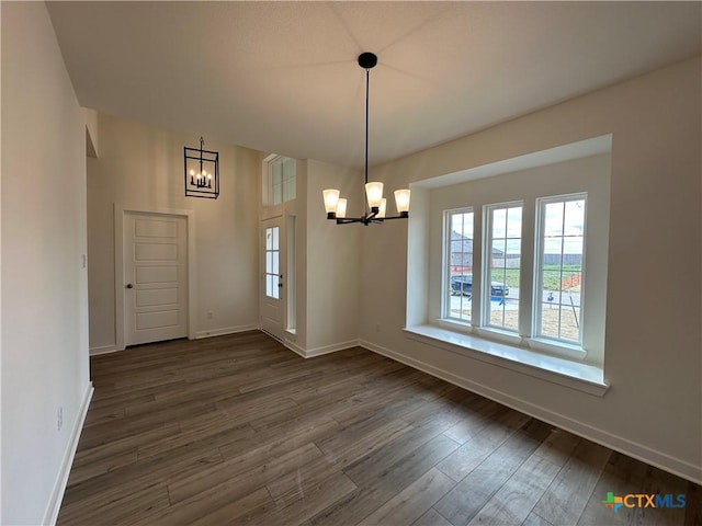 unfurnished dining area with baseboards, dark wood-type flooring, and an inviting chandelier