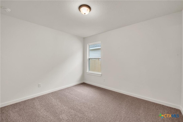 carpeted spare room featuring baseboards