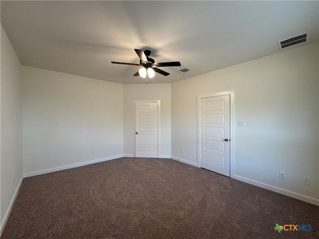 unfurnished bedroom with visible vents, dark carpet, baseboards, and ceiling fan