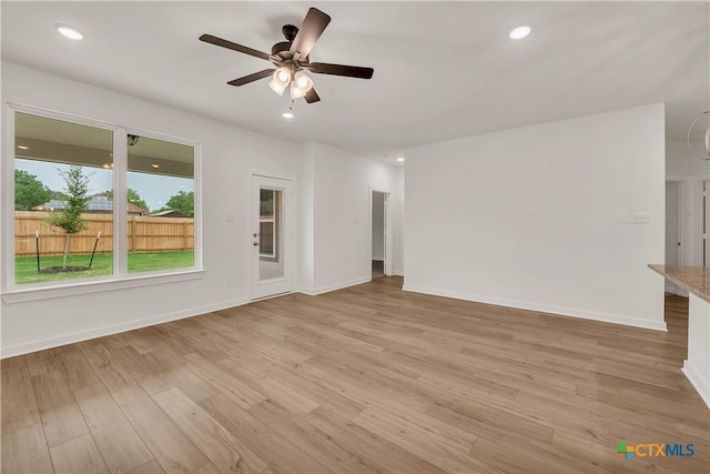 unfurnished living room featuring recessed lighting, light wood-style flooring, a ceiling fan, and baseboards