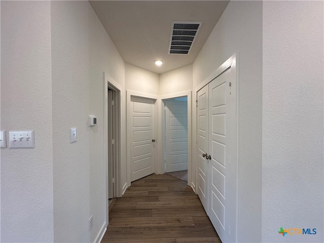 hallway featuring visible vents and dark wood-style flooring