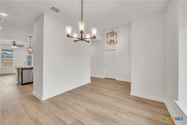 unfurnished dining area with baseboards, light wood-style floors, visible vents, and ceiling fan with notable chandelier