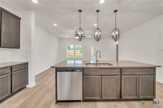 kitchen featuring stainless steel dishwasher, light stone counters, a sink, and an inviting chandelier
