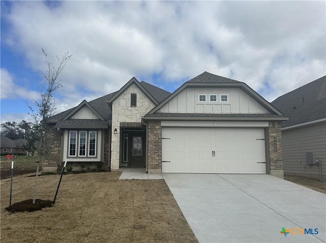 view of front facade with board and batten siding, concrete driveway, a shingled roof, a garage, and brick siding