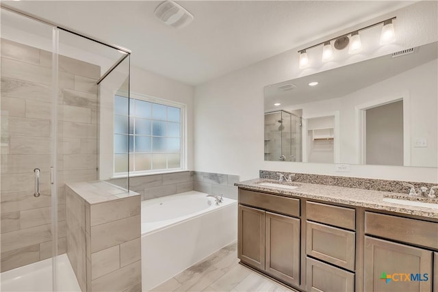 bathroom featuring a shower stall, visible vents, a garden tub, and a sink