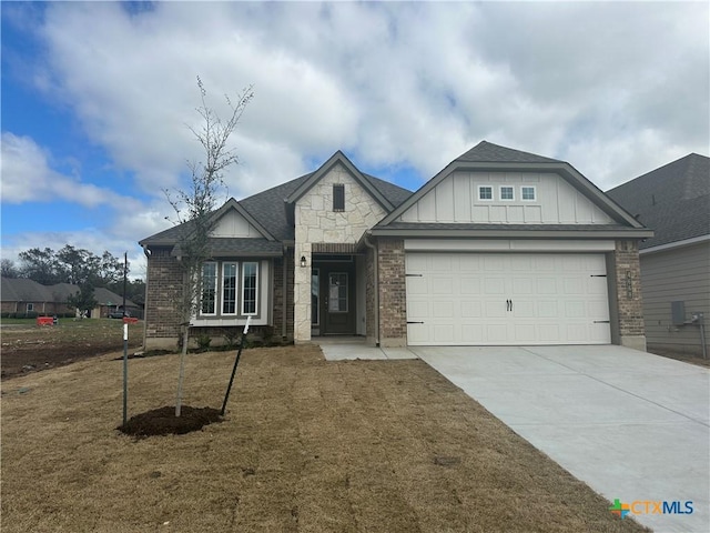 view of front facade with brick siding, board and batten siding, driveway, and a garage