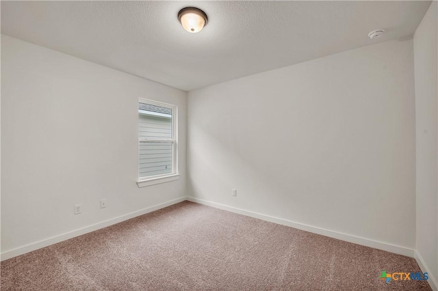 spare room featuring a textured ceiling, carpet flooring, and baseboards