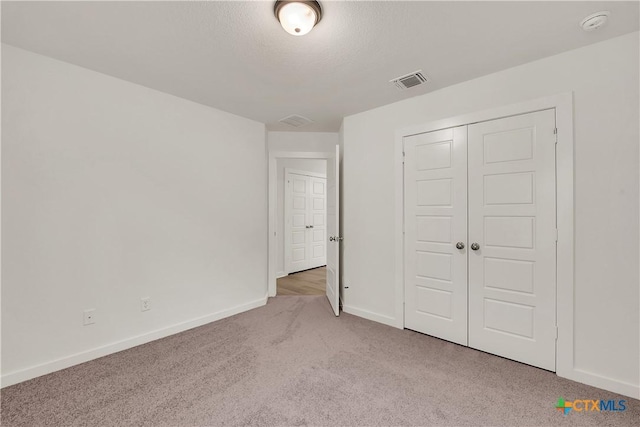 unfurnished bedroom with light colored carpet, baseboards, visible vents, and a closet