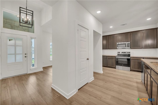 kitchen with light wood finished floors, baseboards, visible vents, dark brown cabinetry, and appliances with stainless steel finishes