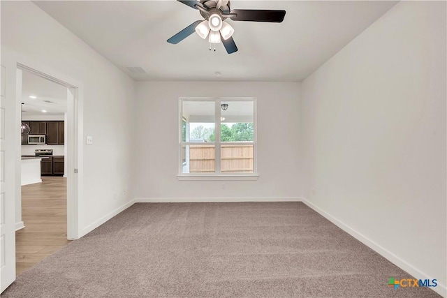 unfurnished room with ceiling fan, baseboards, visible vents, and light carpet