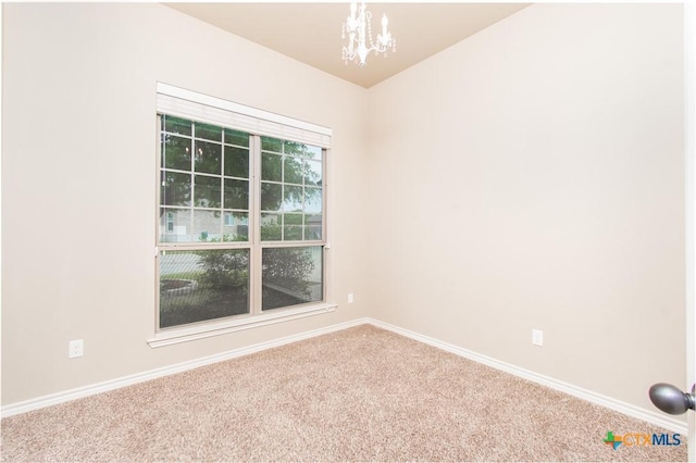 empty room with baseboards, an inviting chandelier, and carpet