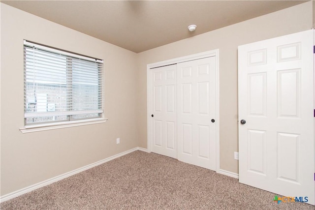 unfurnished bedroom featuring carpet floors, baseboards, and a closet