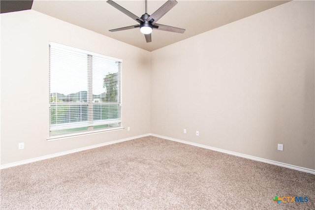 carpeted spare room featuring baseboards and a ceiling fan