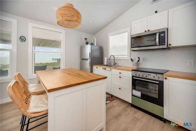 1707 N Ocean Dr, Port Lavaca, TX 77979 - kitchen with butcher block counters, appliances with stainless steel finishes, a sink, lofted ceiling, and light wood-style flooring
