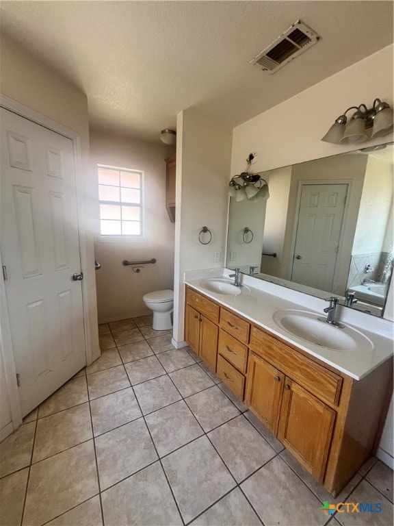 bathroom with toilet, vanity, a textured ceiling, and tile patterned flooring