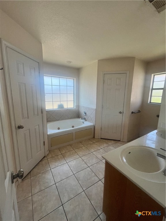 bathroom with a bath, a textured ceiling, tile patterned floors, and plenty of natural light