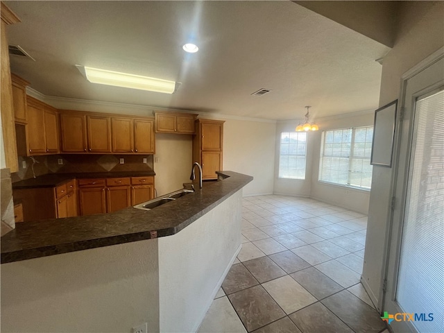 kitchen featuring kitchen peninsula, a notable chandelier, sink, ornamental molding, and light tile patterned flooring